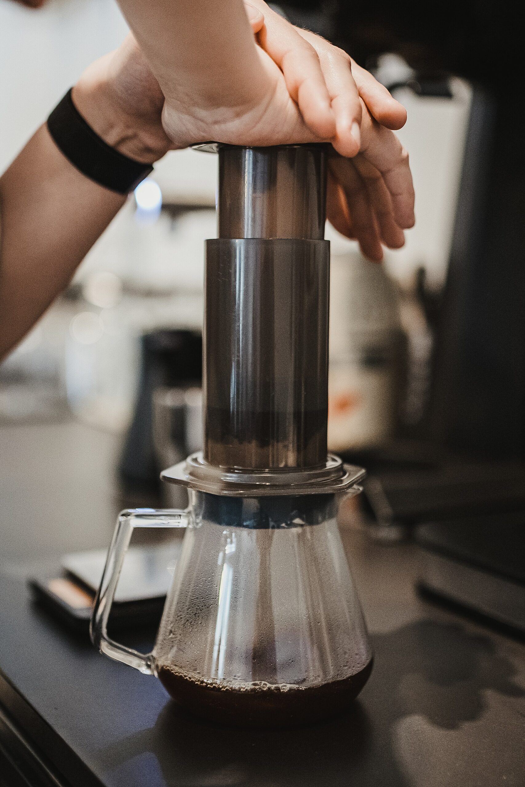A hand pressing an AeroPress over a glass carafe, the heart of the aeropress vs french press choice