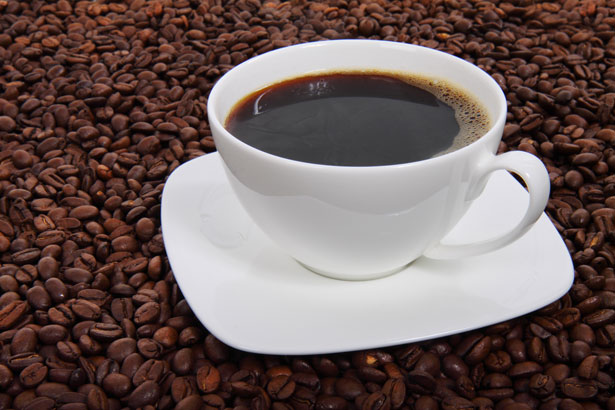 Coffee cup surrounded by beans, illustrating how to make strong coffee at home