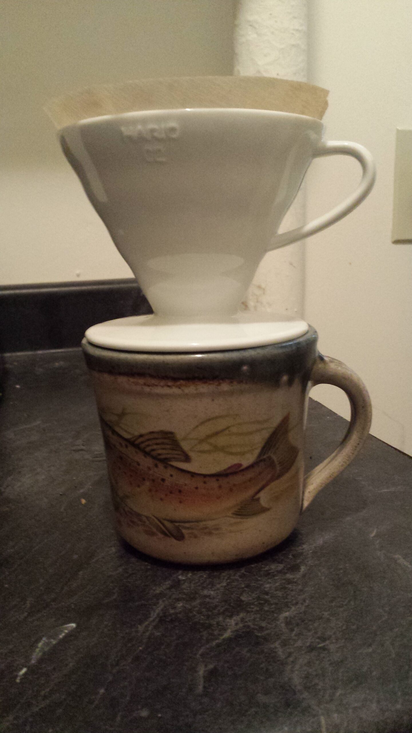 A white cone dripper on a mug, ready for a coffee bloom pour