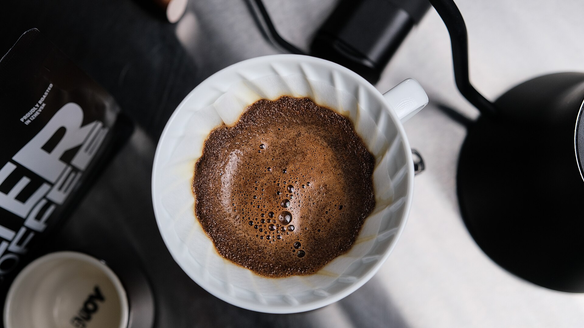 A V60 coffee bed blooming after the first pour, showing the coffee bloom as gas escapes