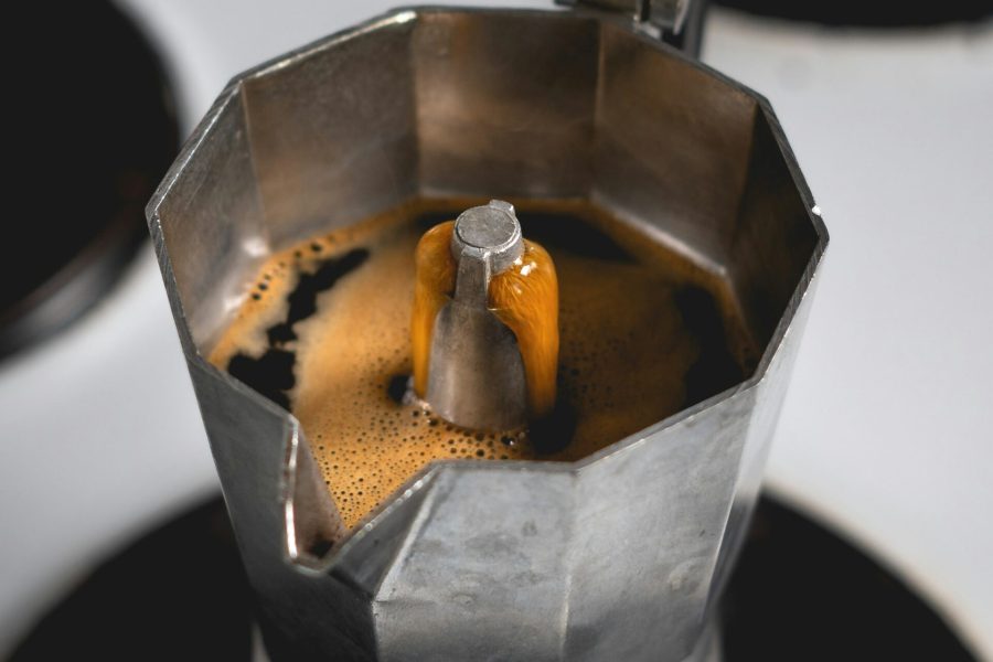 Moka pot on the stove with coffee rising into the upper chamber