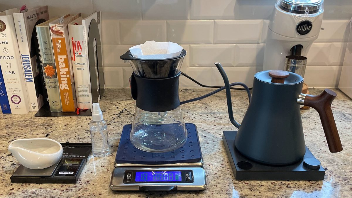 A home pour over setup with a digital scale, dripper and gooseneck kettle for measuring the coffee to water ratio