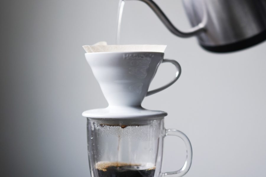 Pouring hot water over coffee with a gooseneck kettle and scale, an example of coffee water temperature control