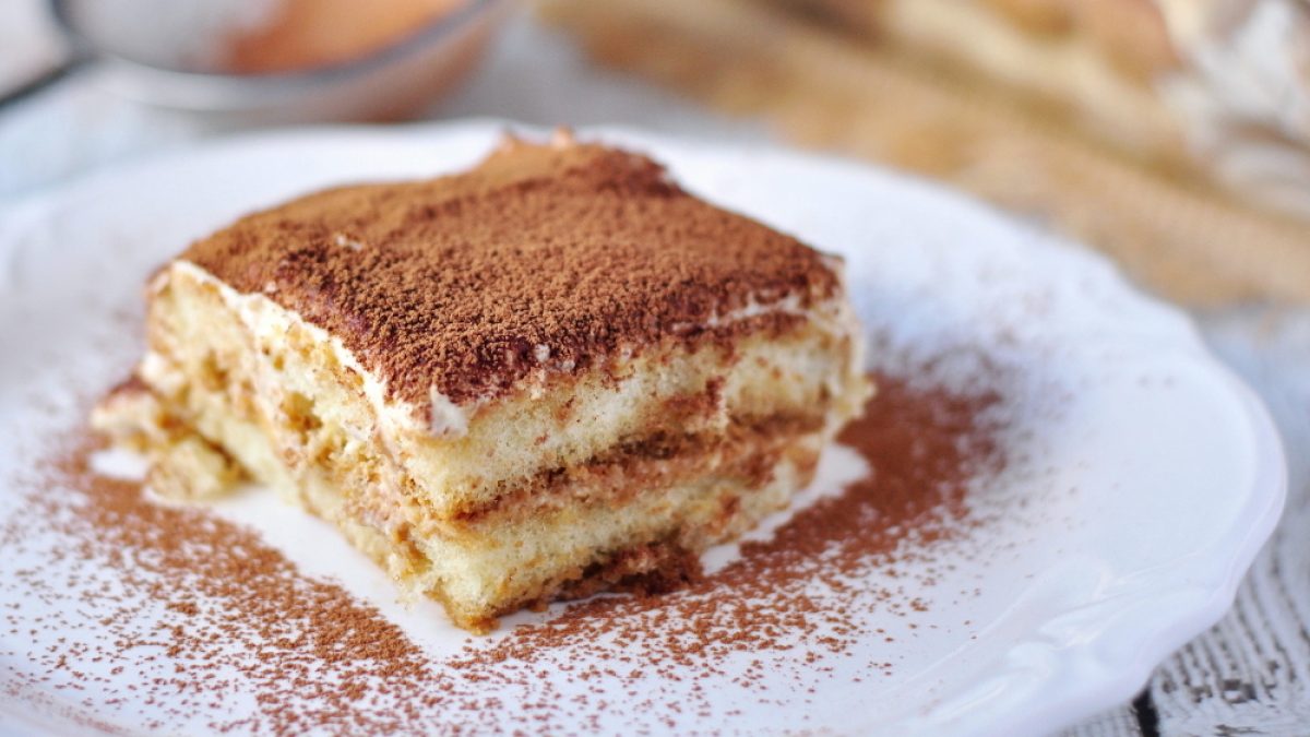 A slice of classic Italian tiramisu dusted with cocoa, a dessert whose history begins in northeast Italy